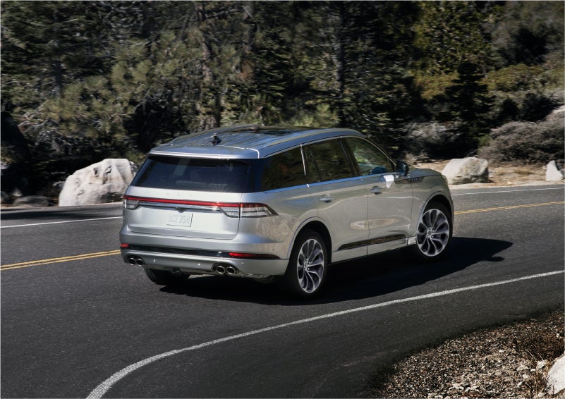 A 2023 Lincoln Aviator® Grand Touring model is shown being driven on a tight turn of a mountain road | Lincoln of Coconut Creek in Coconut Creek FL