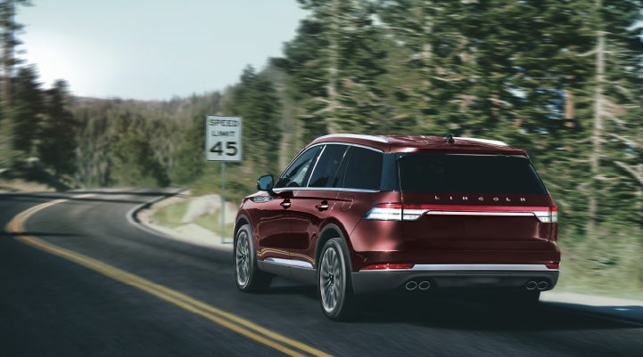 A 2024 Lincoln Aviator® SUV is being driven on a winding mountain road | Lincoln of Coconut Creek in Coconut Creek FL
